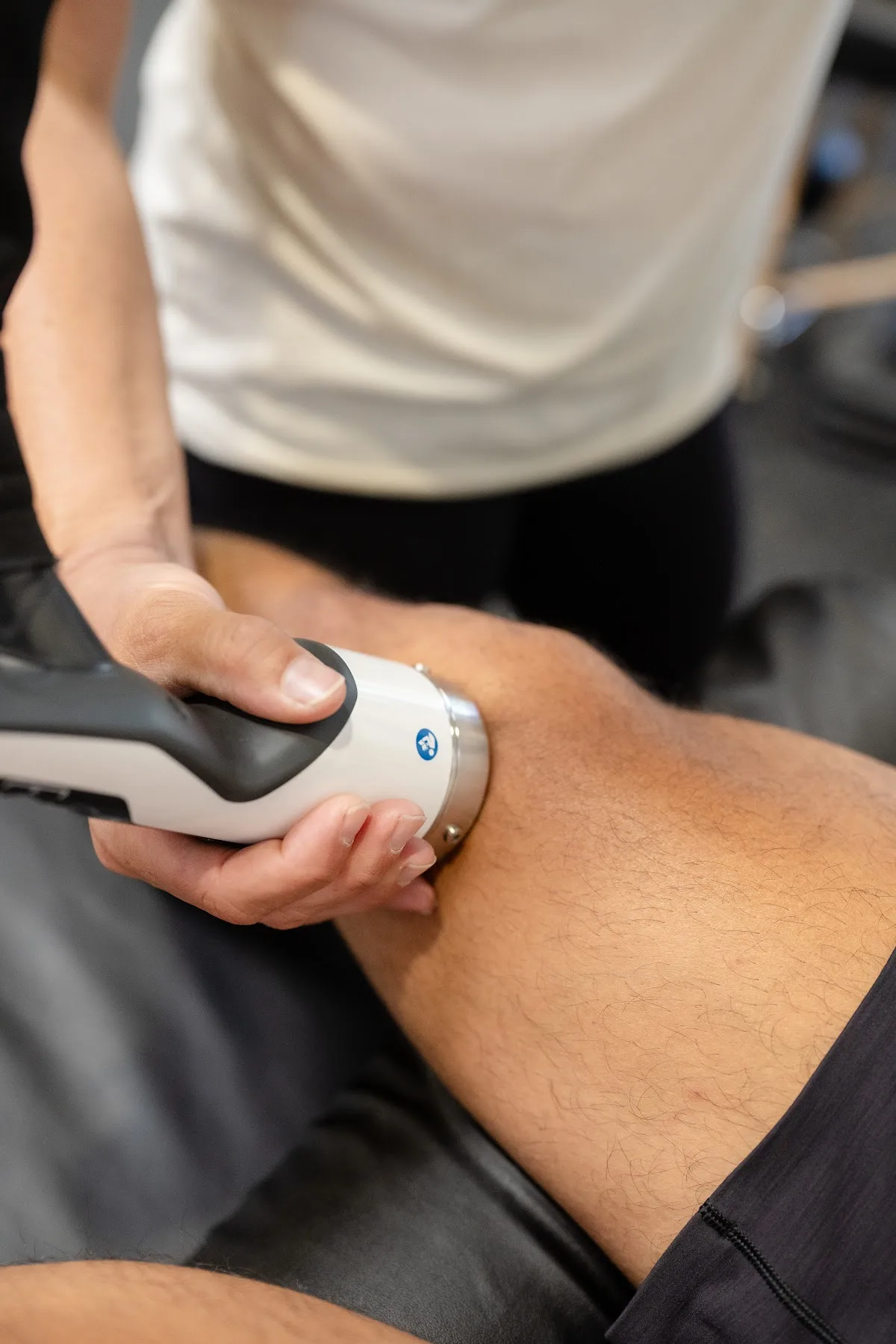 Close-up of a shockwave therapy handpiece treating the knee at the Chula Vista clinic